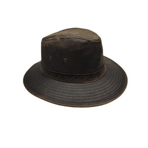 May include: A dark brown leather hat with a wide brim and a slightly distressed appearance. The hat features a structured crown with two small eyelets and a band around the base of the crown. The brim is stitched for durability.