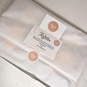 May include: A white gift box with a white tissue paper liner. The box contains a small gift card with the text "Melissa" and "Here's a little treat to say we're thinking of you. Missing you lots and can't wait to see you soon. Stay positive!! love Lucy and Marley xxx" and a small round sticker with the text "Biscuit Club".