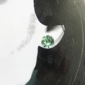 May include: A pair of silver stud earrings with a single green gemstone in each earring.