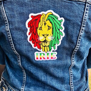 Peut inclure: Une veste en jean avec un patch brodé coloré représentant un lion avec des dreadlocks et le mot "IRIE" en dessous.