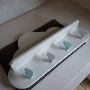 May include: White cloud-shaped wall shelf with four hooks. The hooks are shaped like raindrops and are painted in shades of blue and gray.