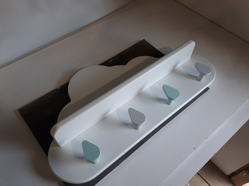 May include: White cloud-shaped wall shelf with four hooks. The hooks are shaped like raindrops and are painted in shades of blue and gray.