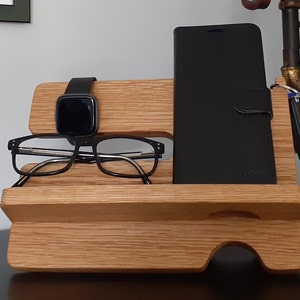 May include: A wooden organizer with a phone stand, watch holder, and glasses holder. The organizer is made of light brown wood and has a natural finish.