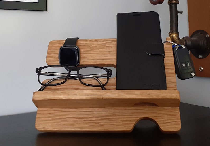 May include: A wooden organizer with a phone stand, watch holder, and glasses holder. The organizer is made of light brown wood and has a natural finish.