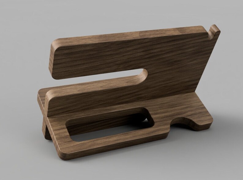 May include: A wooden phone stand with a slot for a phone and a cutout for charging cables. The stand is made of dark brown wood and has a natural wood grain.