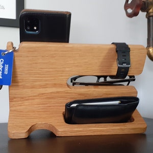May include: Wooden organizer with slots for a phone, watch, glasses, and wallet. The organizer is made of light brown wood and has a blue Tesco Clubcard attached to it.