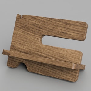 May include: A wooden phone stand with a shelf for charging or holding a phone. The stand is made of light brown wood with a natural grain pattern.