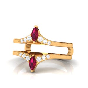 Könnte beinhalten: Ein goldfarbener Ring mit einem Doppelband-Design. Jedes Band hat einen marquiseförmigen Rubin-Edelstein und eine Reihe kleiner, runder, weißer Edelsteine. Der Ring ist vor einem weißen Hintergrund.