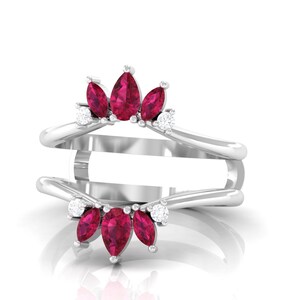 May include: A silver ring with a double band design. The ring features a cluster of five pear-shaped, deep red gemstones and small, round white gemstones. The gemstones are set in a decorative pattern.