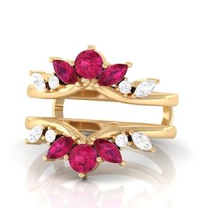 May include: A gold-colored ring guard with a floral design. The ring features round and marquise-cut ruby gemstones and small white diamonds. The ring is designed to be worn with another ring, creating a layered effect.