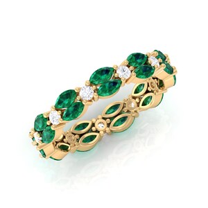 Op de afbeelding: Een gouden ring met een herhalend patroon van marquise-geslepen smaragden en ronde witte diamanten. Het ontwerp van de ring bevat een bloemmotief, met de edelstenen gezet in een delicate, sierlijke band.