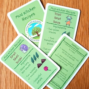 May include: Four green recipe cards with illustrated images and text. The cards are for a game called "Mud Kitchen Recipes" and feature recipes for "Troll Snot Soup", "Snail Shell Sushi", and two other recipes. The cards are made by Little Wood Walkers.
