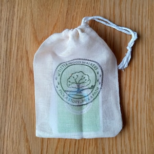 May include: A white cotton drawstring bag with a green and brown logo that says "Little Wood Walkers Pick a Story, Pick a Path".