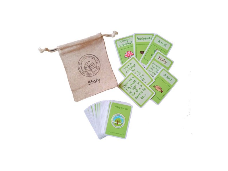 May include: A set of story cards with illustrations and text, alongside a drawstring bag. The cards feature images of a toadstool, footprints, a troll, and a nest. The bag is beige and has the word "Story" printed on it.