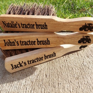 May include: Three wooden brushes with black tractor designs and personalised names. The brushes are stacked on top of each other. The top brush says "Natalie's tractor brush", the middle brush says "John's tractor brush", and the bottom brush says "Jack's tractor brush".