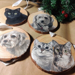 4 custom hand painted pet portraits on wood slice ornaments with white ribbon. Detailed and realistic painted cat and dog portraits. 1 ornament with a black cat, 2 with different Bichon Frises, and one ornament with 2 cats, grey and brown tabbies.