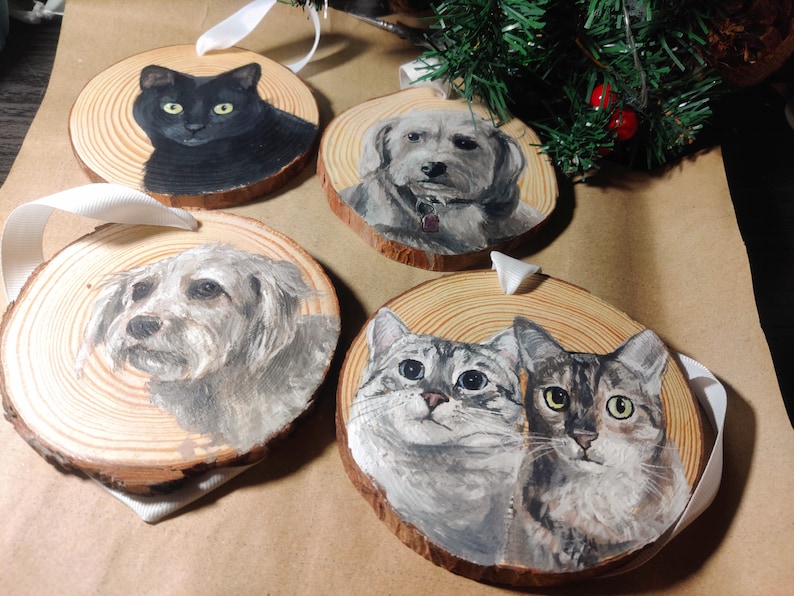 4 custom hand painted pet portraits on wood slice ornaments with white ribbon. Detailed and realistic painted cat and dog portraits. 1 ornament with a black cat, 2 with different Bichon Frises, and one ornament with 2 cats, grey and brown tabbies.
