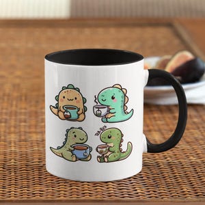 May include: White ceramic mug with a black rim and handle. The mug features a cartoon illustration of four dinosaurs drinking tea. The text "Tea-Rex" is printed on the mug.