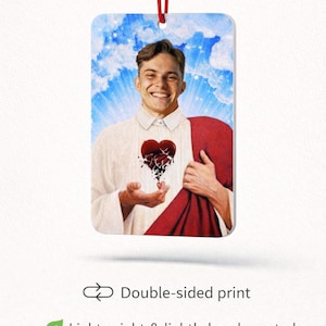 May include: Rectangular air freshener featuring a smiling person in a white shirt and red drape, a broken heart graphic, and a blue sky background. The air freshener has a red string for hanging. Text reads "Double-sided print" and "Lightweight & lightly hand scented."