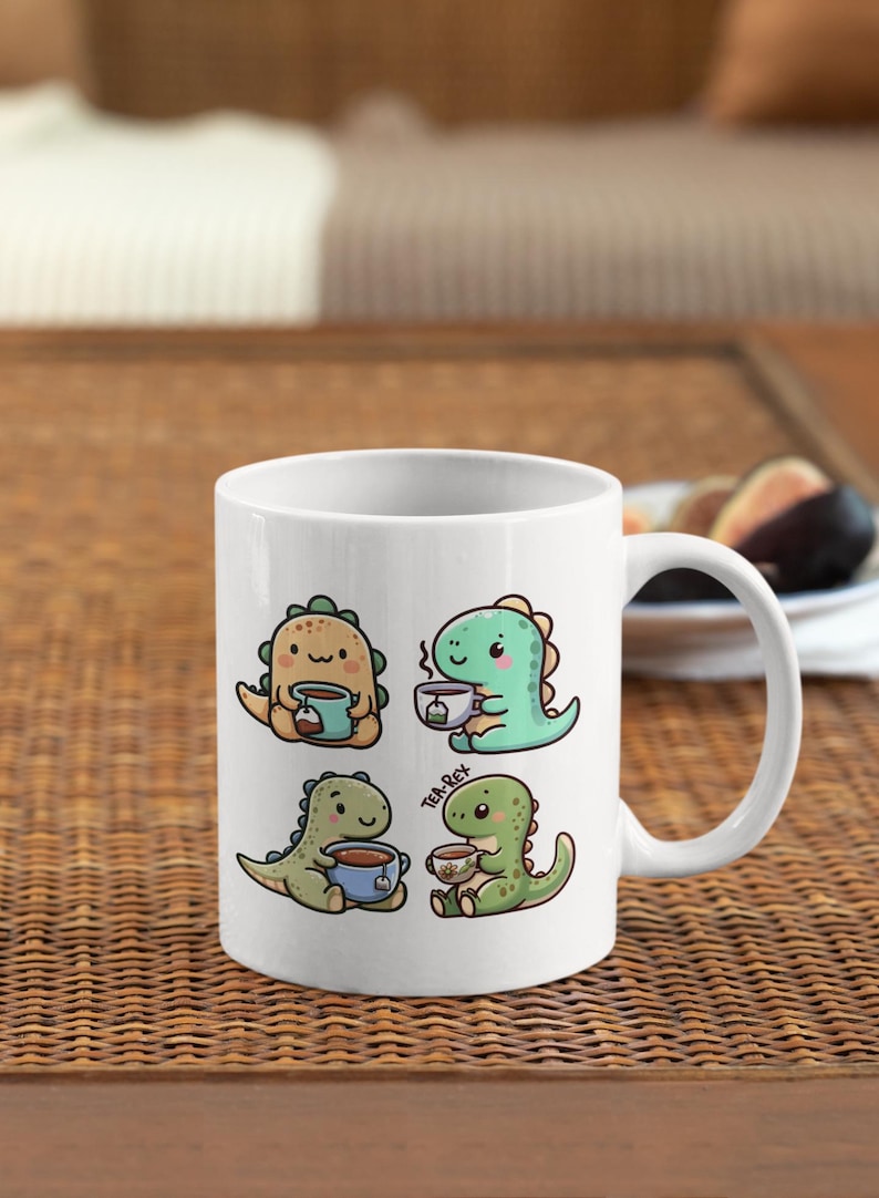 May include: White ceramic mug with a graphic of four cartoon dinosaurs drinking tea. The dinosaurs are green, yellow, and blue. The text "Tea-Rex" is printed on the mug.