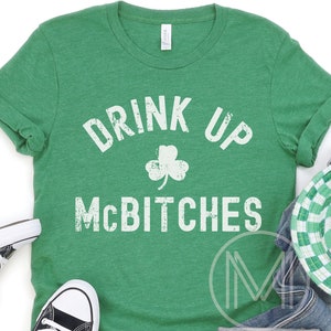May include: Green t-shirt with a white distressed graphic that says "Drink Up McBitches" with a shamrock in the middle.