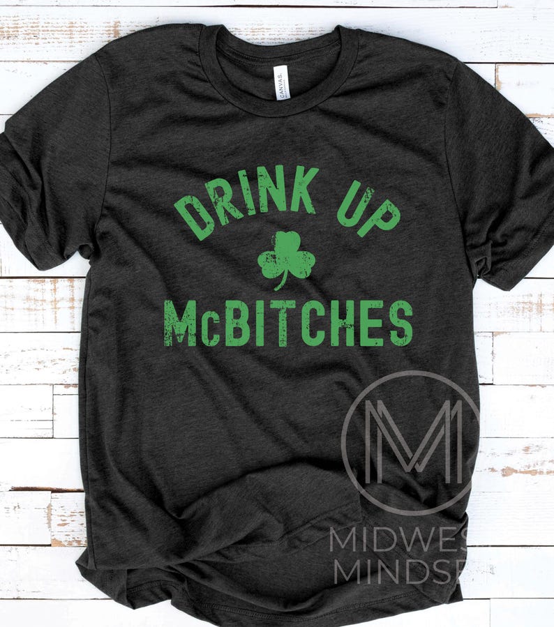 May include: A dark grey t-shirt with a green shamrock and the text "Drink Up McBitches" in a distressed font.