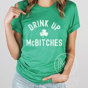 May include: Green t-shirt with white text that reads "Drink Up McBitches" and a shamrock graphic.
