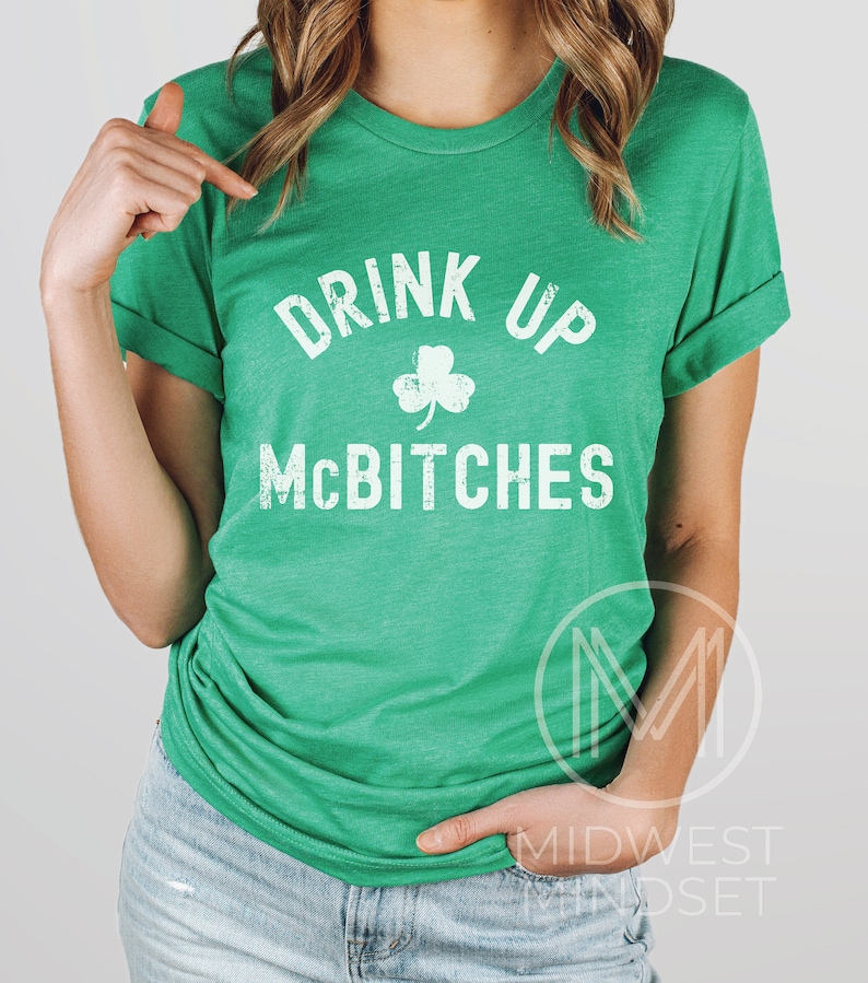 May include: Green t-shirt with white text that reads "Drink Up McBitches" and a shamrock graphic.
