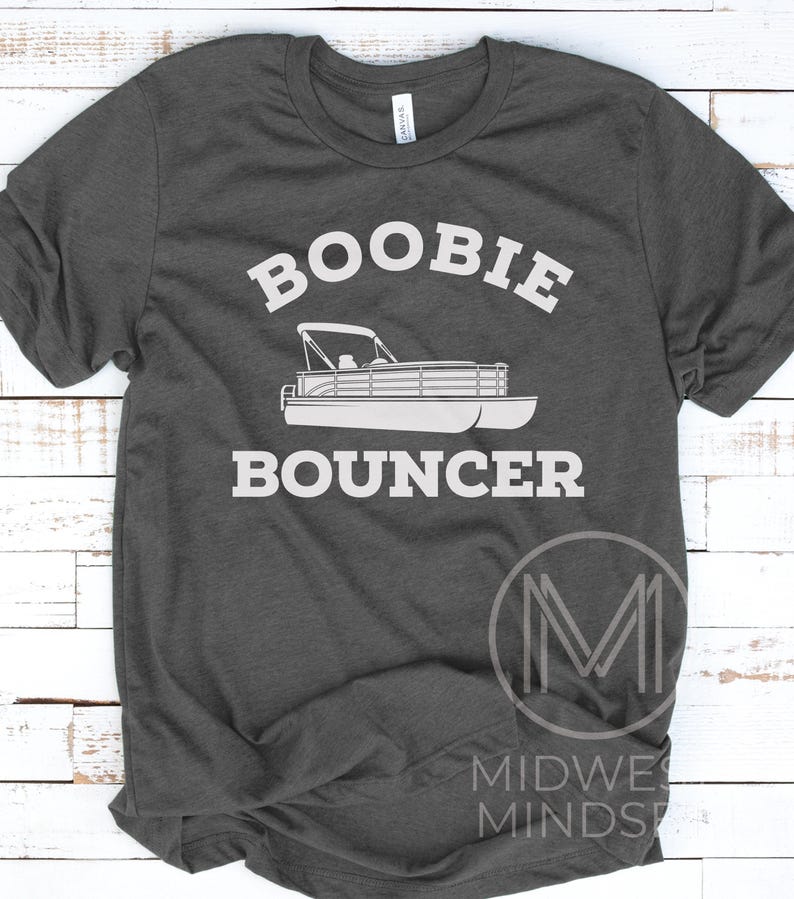 May include: A dark gray t-shirt with the text "Boobie Bouncer" in white. A white silhouette of a pontoon boat is below the text.