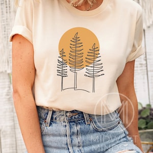 May include: A beige t-shirt with a graphic of three stylized trees in front of a yellow sun.