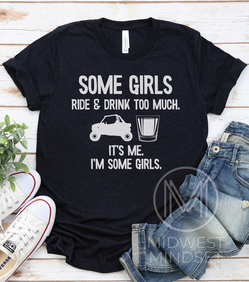 May include: A black t-shirt with white text that reads "Some girls ride & drink too much. It's me. I'm some girls."  The shirt features a graphic of a side-by-side vehicle and a shot glass.