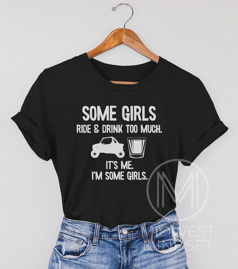 May include: Black t-shirt with white text that reads "Some girls ride & drink too much. It's me. I'm some girls."  The text is accompanied by a graphic of a side-by-side vehicle and a shot glass.