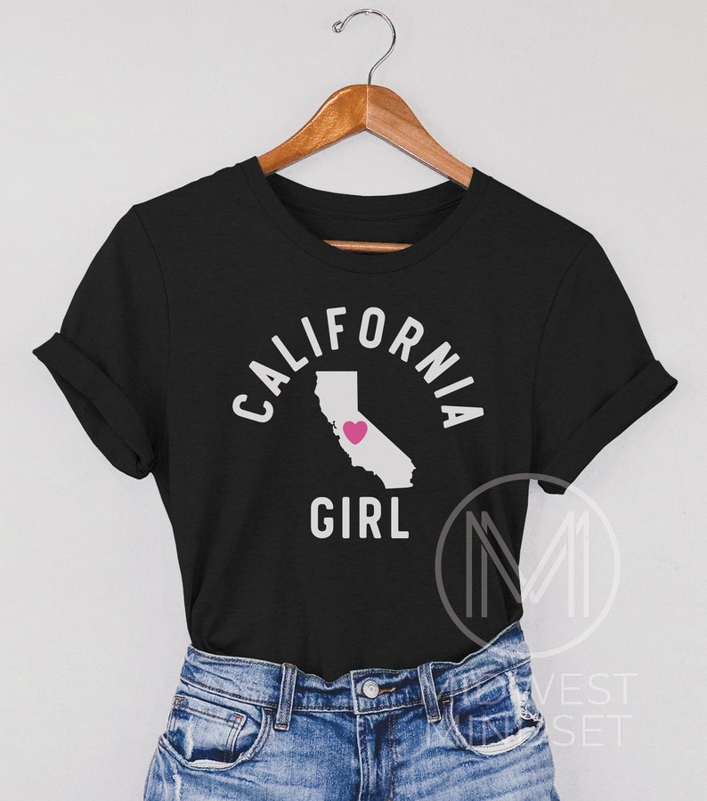 Pu&ograve; includere: Maglietta nera con un contorno bianco dello stato della California e le parole "California Girl" con un cuore rosa all'interno del contorno dello stato.