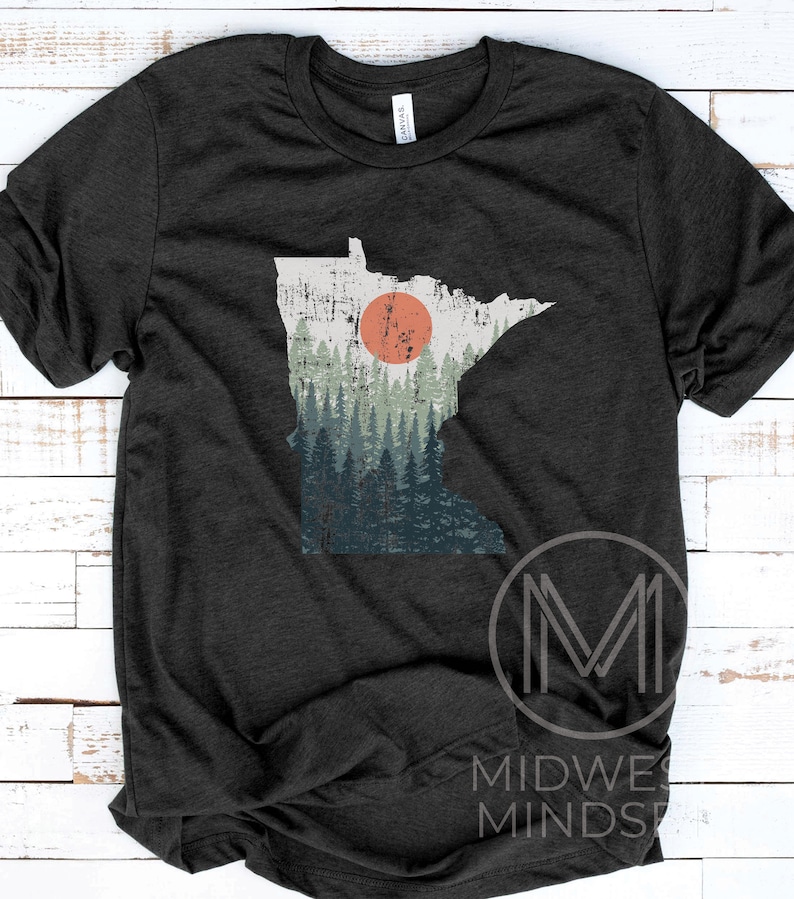 May include: A dark heather grey t-shirt featuring a vintage-style outline of the state of Minnesota with a forest scene and a red sun.