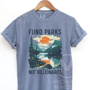 May include: A blue t-shirt with a graphic of a mountain landscape and the text "Fund Parks Not Billionaires".