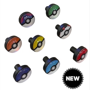 May include: A collection of colorful, round cabinet knobs with black stems, each featuring a different design inspired by a popular animated series. The knobs are white, red, yellow, blue, and green with black accents. A black and white "NEW" sticker is in the image.
