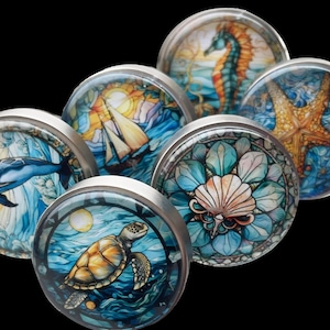 May include: Six round, silver-toned cabinet knobs with colorful, ocean-themed images. The images include a dolphin, a sailboat, a seashell, a starfish, a seahorse, and a sea turtle.