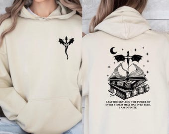 May include: A cream-colored hoodie with a black dragon design on the left side and a black dragon with a stack of books and the text "I am the sky and the power of every storm that has even been. I am infinite." on the right side.