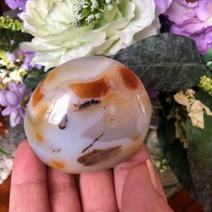 May include: A smooth, white agate stone with brown and orange banding. The stone is polished and has a glossy finish.