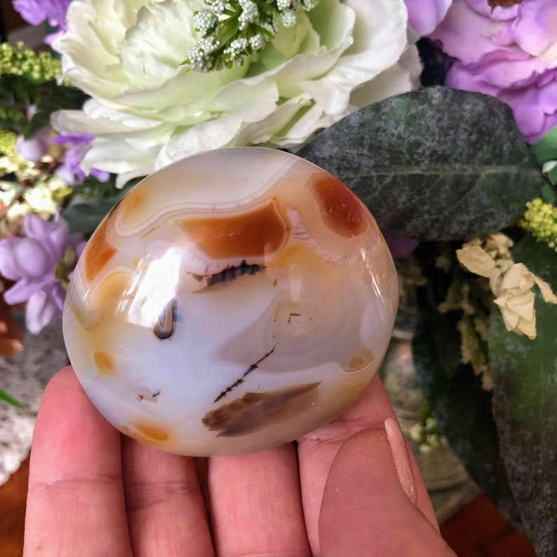 May include: A smooth, white agate stone with brown and orange banding. The stone is polished and has a glossy finish.