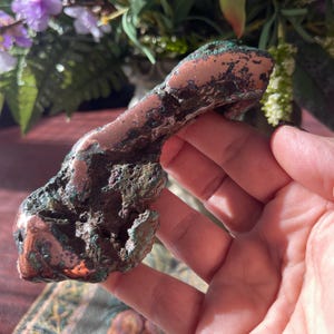 May include: A large, rough, copper nugget with a reddish-brown color and a green patina. The nugget has an irregular shape and is about the size of a hand.