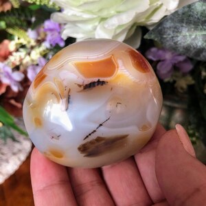 May include: A smooth, white agate sphere with brown and orange banding. The sphere is polished and has a translucent appearance.