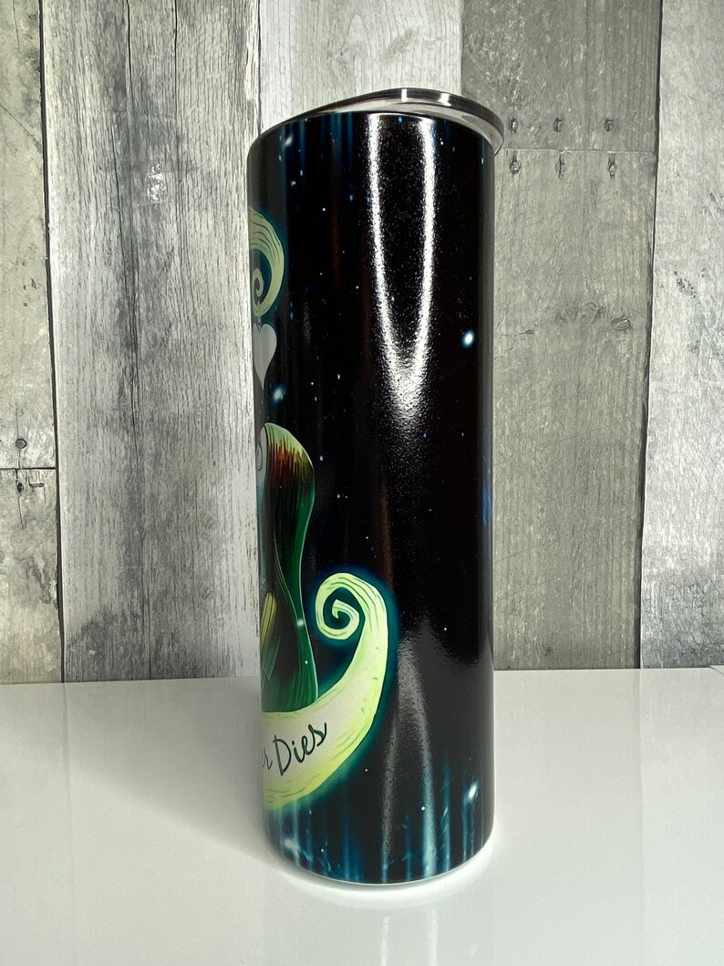 May include: A black and green stainless steel tumbler with a graphic of a character from the movie "The Nightmare Before Christmas". The character is holding a heart and the text "This is Halloween" is visible on the tumbler.