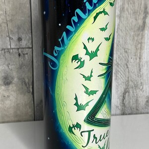 May include: A black and green stainless steel tumbler with a moon and bats design. The text "Jazmin" and "True Love" are printed on the tumbler.
