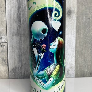May include: A black and blue stainless steel tumbler with a graphic of Jack Skellington and Sally from the Nightmare Before Christmas movie. The graphic shows them holding a rose and the text "Love Never Dies".