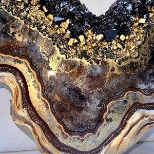 Op de afbeelding: Een kunstharswerk met een goud-zwart agaatontwerp. Het stuk heeft een bruin, goud en zwart kleurenschema en een golvende, organische vorm.