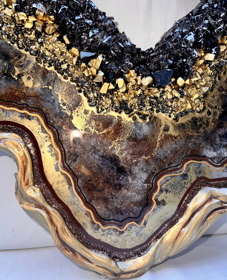 Op de afbeelding: Een kunstharswerk met een goud-zwart agaatontwerp. Het stuk heeft een bruin, goud en zwart kleurenschema en een golvende, organische vorm.