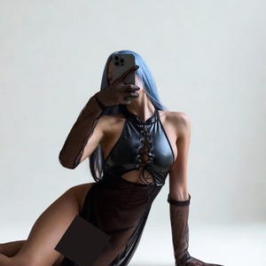 May include: A black halter dress with a lace-up bodice and a sheer skirt. The dress is paired with sheer gloves. The person in the image has blue hair and is holding a phone.