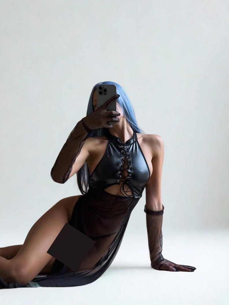 May include: A black halter dress with a lace-up bodice and a sheer skirt. The dress is paired with sheer gloves. The person in the image has blue hair and is holding a phone.