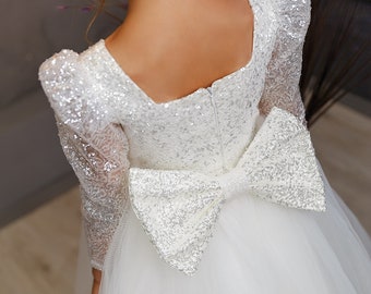 May include: White tulle dress with a silver sequin bodice and a large silver sequin bow at the back.
